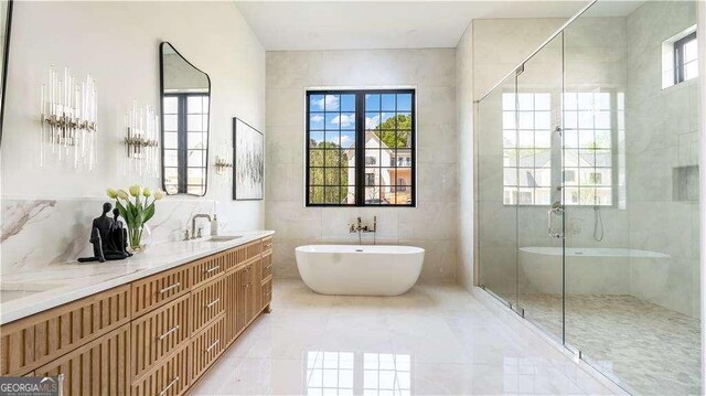 full bathroom featuring a shower stall, a sink, tile walls, a freestanding bath, and double vanity