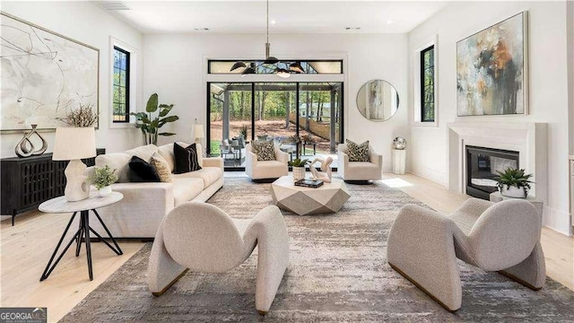 living area with wood finished floors, a glass covered fireplace, and visible vents