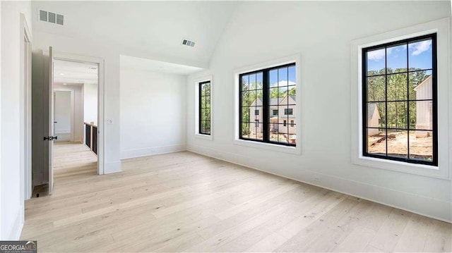 spare room with light wood finished floors, visible vents, and baseboards
