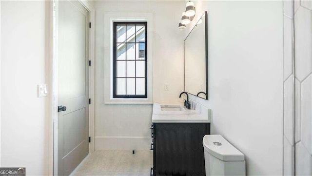 bathroom featuring tile patterned flooring, vanity, baseboards, and toilet