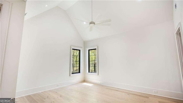 empty room featuring baseboards, high vaulted ceiling, wood finished floors, and a ceiling fan