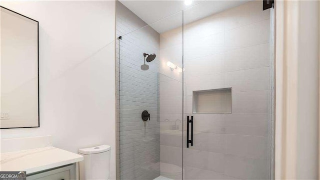 bathroom featuring toilet, a stall shower, and vanity