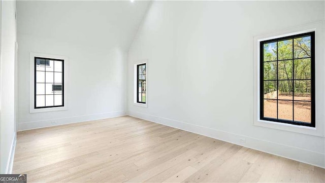 empty room with baseboards, light wood finished floors, and vaulted ceiling
