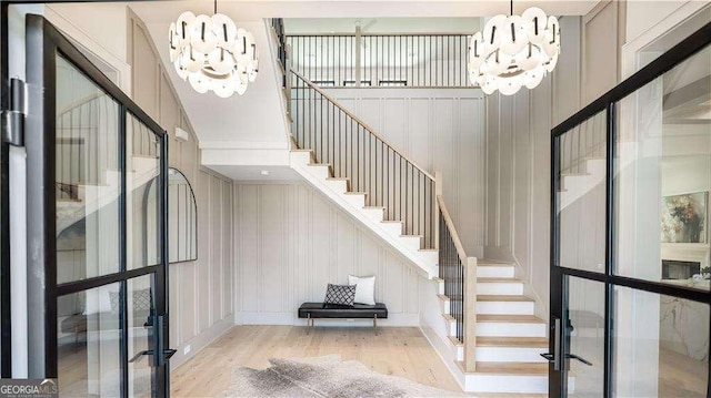 foyer entrance with wood finished floors, an inviting chandelier, a decorative wall, and stairway