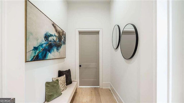 corridor featuring light wood finished floors and baseboards