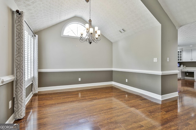 135 Fairway Ct, Newnan, GA 30265 - unfurnished dining area with a textured ceiling, vaulted ceiling, wood finished floors, a chandelier, and baseboards