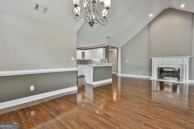 135 Fairway Ct, Newnan, GA 30265 - unfurnished living room featuring lofted ceiling, baseboards, dark wood finished floors, a chandelier, and a premium fireplace
