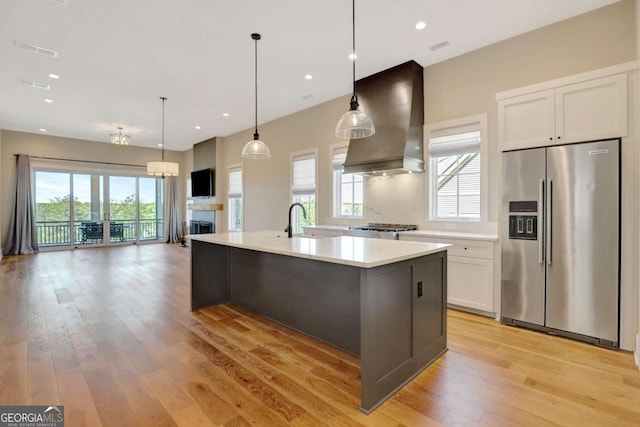 1130 Lupo Loop, Chattahoochee Hills, GA 30268 - kitchen featuring high quality fridge, wall chimney range hood, white cabinetry, light wood finished floors, and light countertops