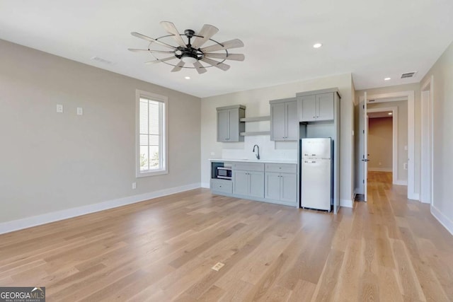 1130 Lupo Loop, Chattahoochee Hills, GA 30268 - kitchen with freestanding refrigerator, gray cabinets, stainless steel microwave, open shelves, and a ceiling fan