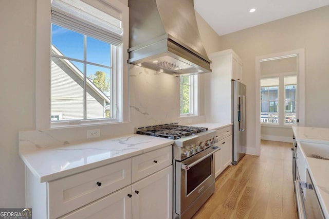 1130 Lupo Loop, Chattahoochee Hills, GA 30268 - kitchen featuring premium appliances, premium range hood, light wood-style flooring, white cabinetry, and healthy amount of natural light
