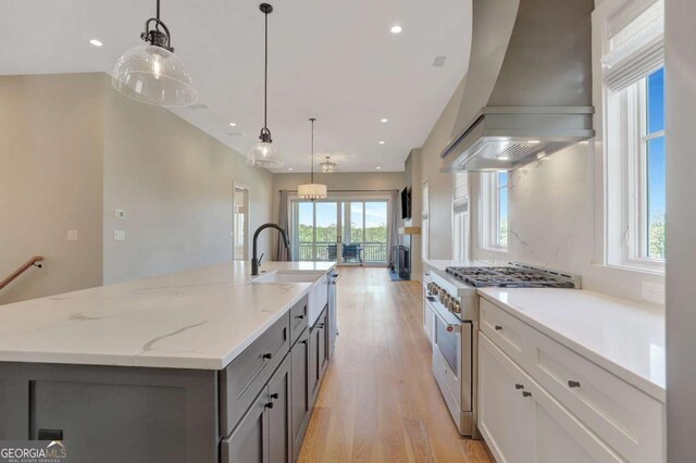 1130 Lupo Loop, Chattahoochee Hills, GA 30268 - kitchen featuring stainless steel stove, custom range hood, light wood-style floors, gray cabinetry, and a center island with sink