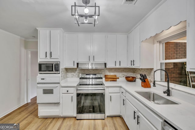 kitchen with under cabinet range hood, decorative backsplash, a sink, and appliances with stainless steel finishes