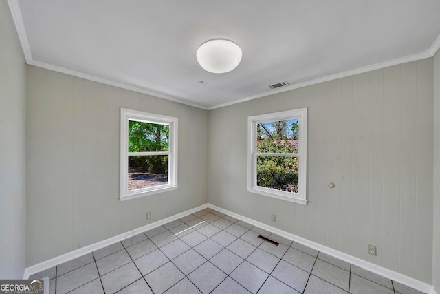 empty room featuring crown molding, light tile patterned floors, and baseboards