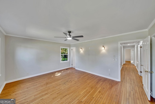 spare room featuring ornamental molding, a ceiling fan, attic access, light wood finished floors, and baseboards