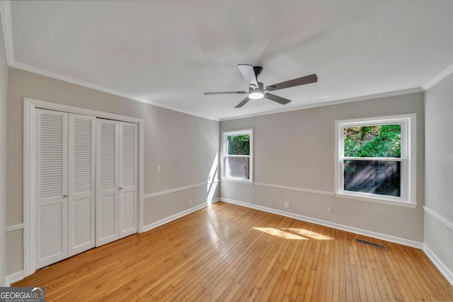 unfurnished bedroom with a closet, baseboards, ornamental molding, visible vents, and light wood finished floors