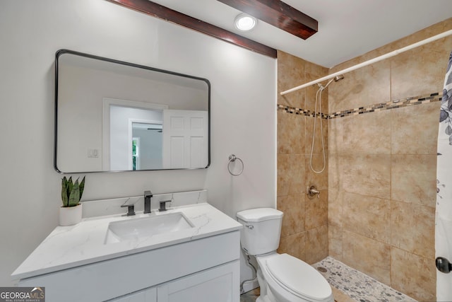 bathroom featuring toilet, a tile shower, and vanity
