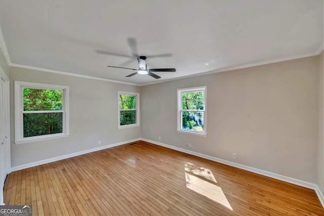 spare room featuring baseboards, ornamental molding, visible vents, hardwood / wood-style floors, and ceiling fan