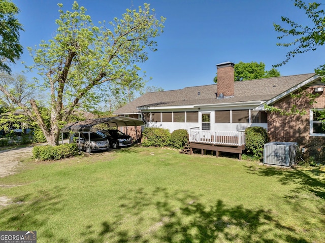 rear view of property featuring central AC, a sunroom, a lawn, a chimney, and a detached carport