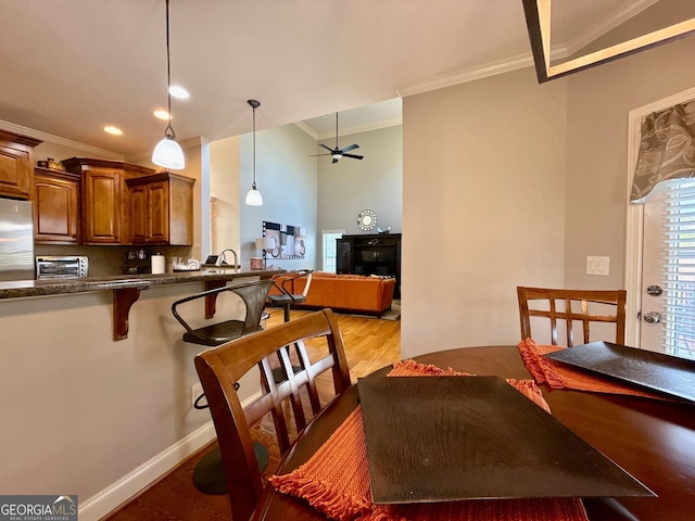 dining area with crown molding, light wood-style flooring, a ceiling fan, and a toaster