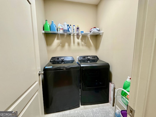 clothes washing area featuring laundry area, washing machine and clothes dryer, and light tile patterned flooring
