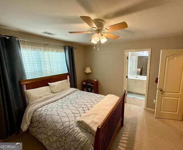 bedroom with visible vents, a sink, a ceiling fan, ensuite bath, and light carpet
