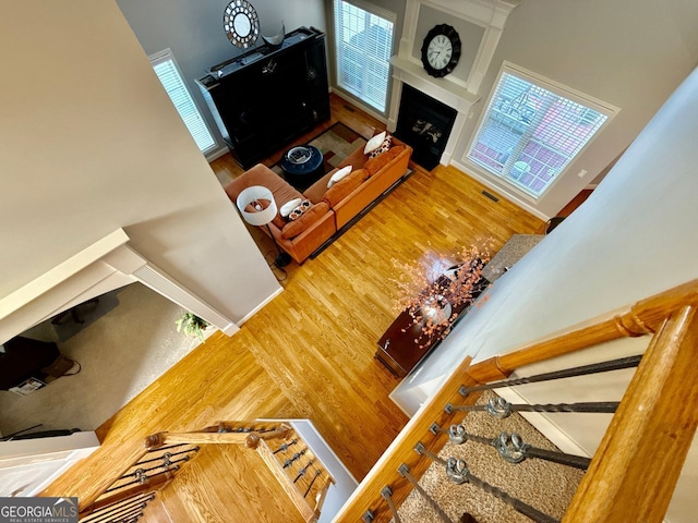 living room featuring wood finished floors, a fireplace, visible vents, and a towering ceiling