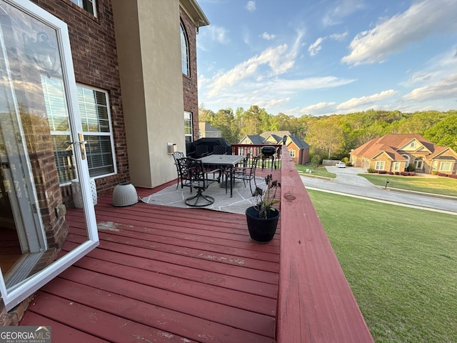 wooden deck with a yard and outdoor dining space