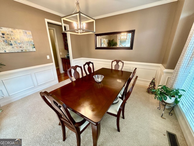 dining room featuring a chandelier, a decorative wall, carpet, and visible vents