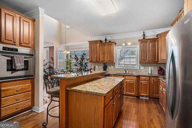 kitchen featuring brown cabinetry, a breakfast bar, backsplash, and stainless steel appliances