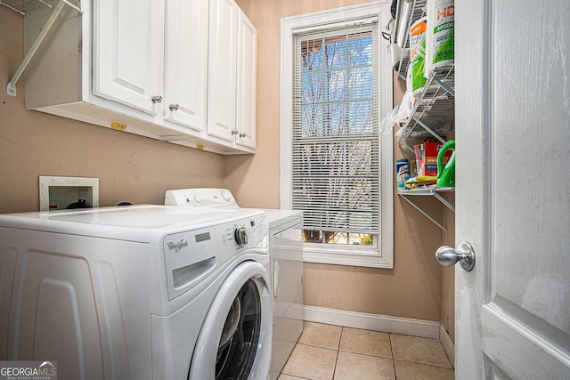 laundry area featuring light tile patterned floors, baseboards, washer and dryer, and a healthy amount of sunlight