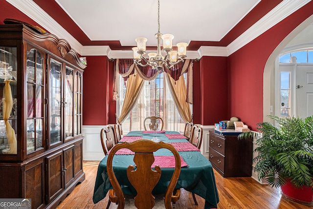 dining area with a chandelier, arched walkways, wainscoting, and crown molding