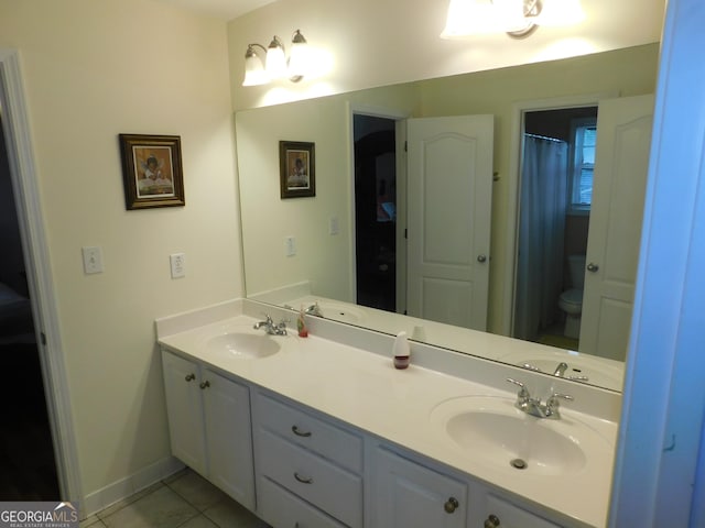 full bath featuring a sink, tile patterned floors, double vanity, and toilet