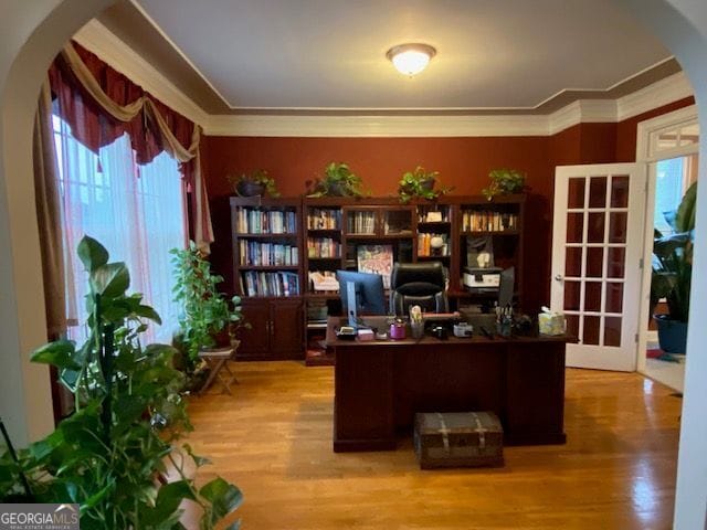 office area with arched walkways, wood finished floors, and a wealth of natural light