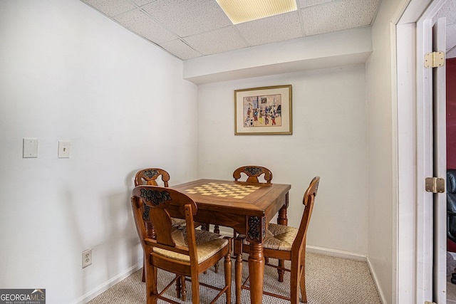 carpeted dining room with baseboards and a drop ceiling