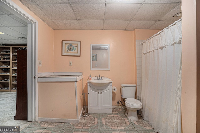 bathroom with toilet, a paneled ceiling, vanity, and tile patterned floors