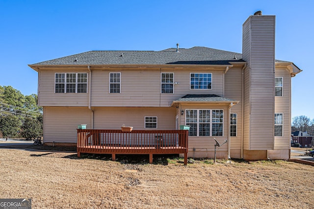 rear view of property featuring a chimney and a wooden deck