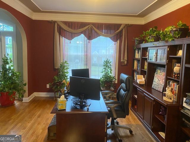 office area with ornamental molding, light wood-style flooring, arched walkways, and baseboards