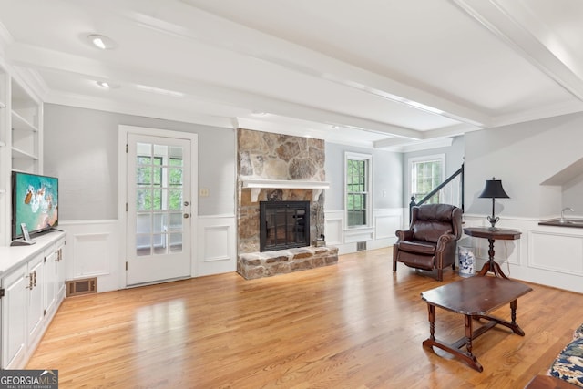 918 Guinevere Way SW, Lilburn, GA 30047 - living area with a wainscoted wall, a fireplace, a decorative wall, beamed ceiling, and light wood-type flooring