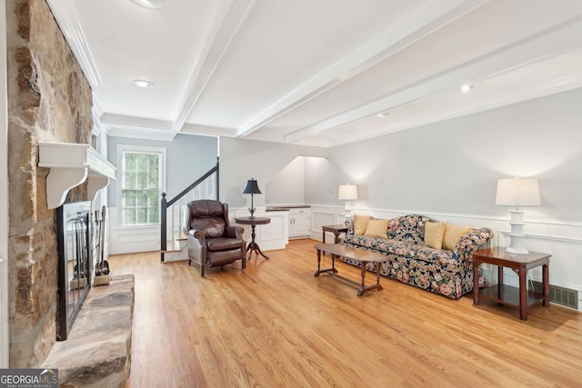 918 Guinevere Way SW, Lilburn, GA 30047 - living area featuring a fireplace with raised hearth, beam ceiling, light wood finished floors, stairway, and wainscoting