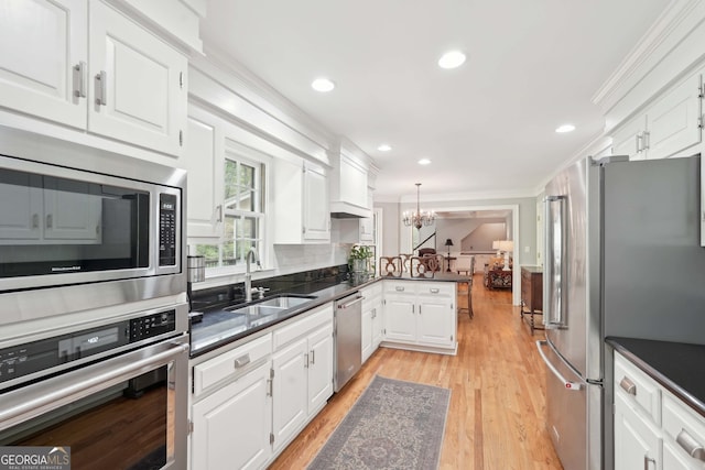 918 Guinevere Way SW, Lilburn, GA 30047 - kitchen featuring appliances with stainless steel finishes, a chandelier, crown molding, a peninsula, and white cabinets