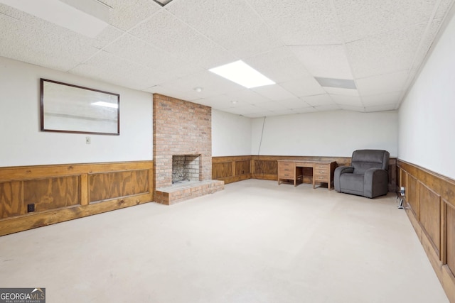 918 Guinevere Way SW, Lilburn, GA 30047 - unfurnished room featuring wainscoting, wood walls, finished concrete floors, a fireplace, and a drop ceiling