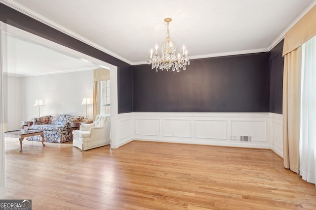 918 Guinevere Way SW, Lilburn, GA 30047 - dining area with a chandelier, light wood-style floors, ornamental molding, a wainscoted wall, and a decorative wall