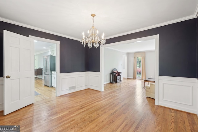 918 Guinevere Way SW, Lilburn, GA 30047 - unfurnished room with a chandelier, ornamental molding, light wood-type flooring, wainscoting, and a decorative wall