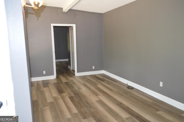 66 Topaz Ln, Royston, GA 30662 - empty room with beam ceiling, baseboards, an inviting chandelier, and wood finished floors