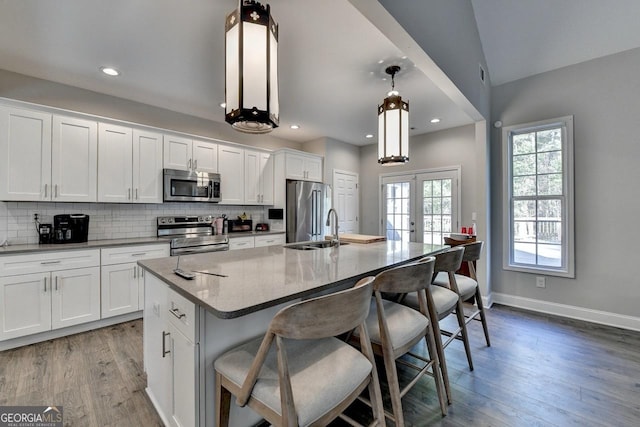 kitchen featuring white cabinets, appliances with stainless steel finishes, a kitchen island with sink, a sink, and french doors