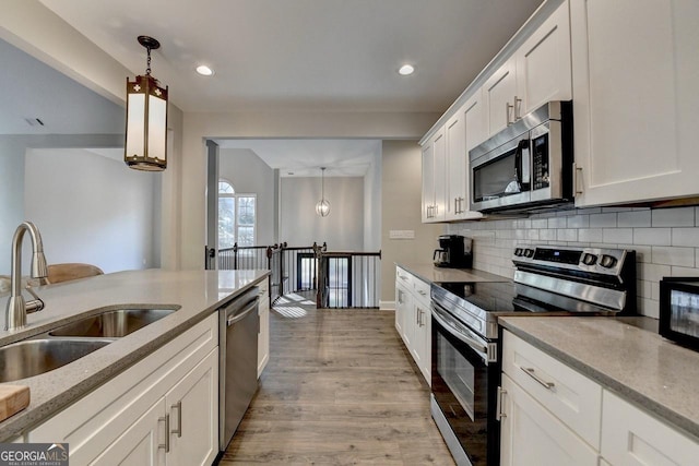 kitchen with stainless steel appliances, tasteful backsplash, light wood-type flooring, and a sink