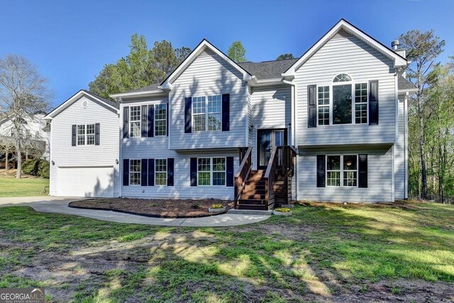 raised ranch with driveway, a front lawn, and an attached garage