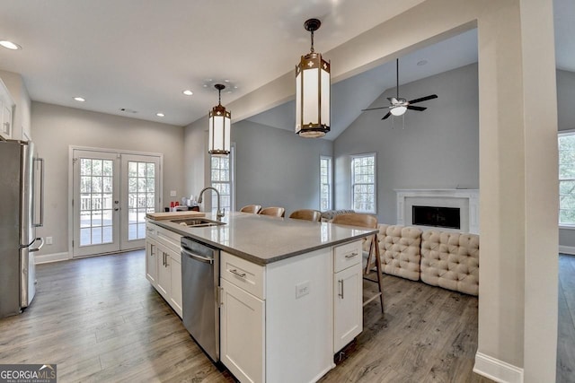 kitchen featuring light wood-type flooring, appliances with stainless steel finishes, a sink, french doors, and a breakfast bar area