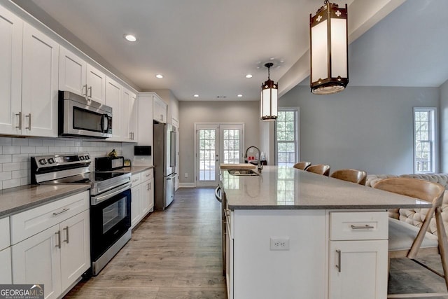 kitchen with a sink, appliances with stainless steel finishes, plenty of natural light, and light wood finished floors
