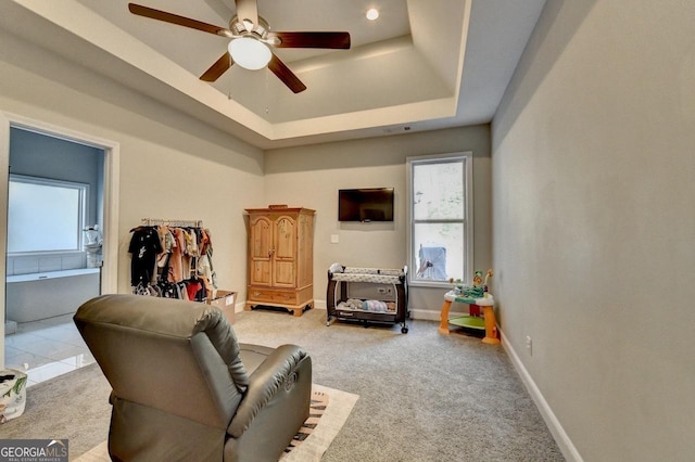 living area with a tray ceiling, a healthy amount of sunlight, ceiling fan, and carpet floors